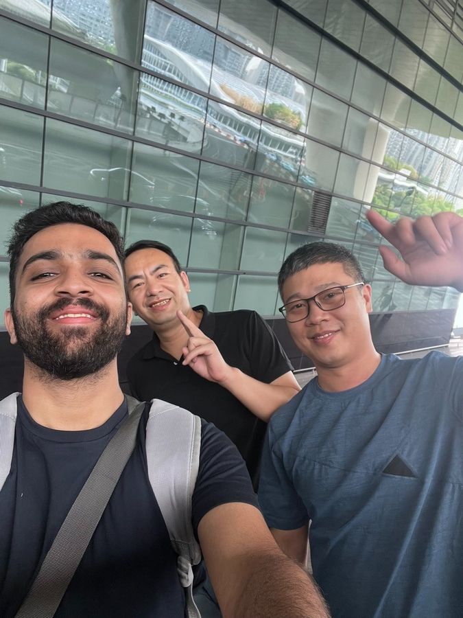 Bhushan with two colleagues outside a glass-fronted building